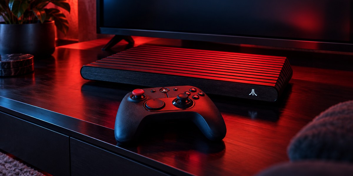 Une console Atari VCS noire à dessus strié et sa manette devant un téléviseur éteint.