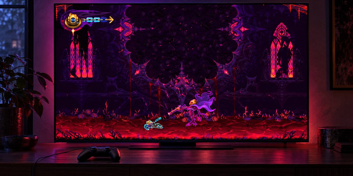 Un téléviseur affiche un combat dans une salle sombre aux vitraux rouges, avec une manette posée devant.